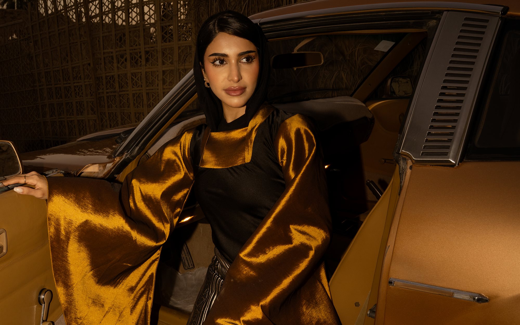 Majd & Thahab, gold cape close-up by the car