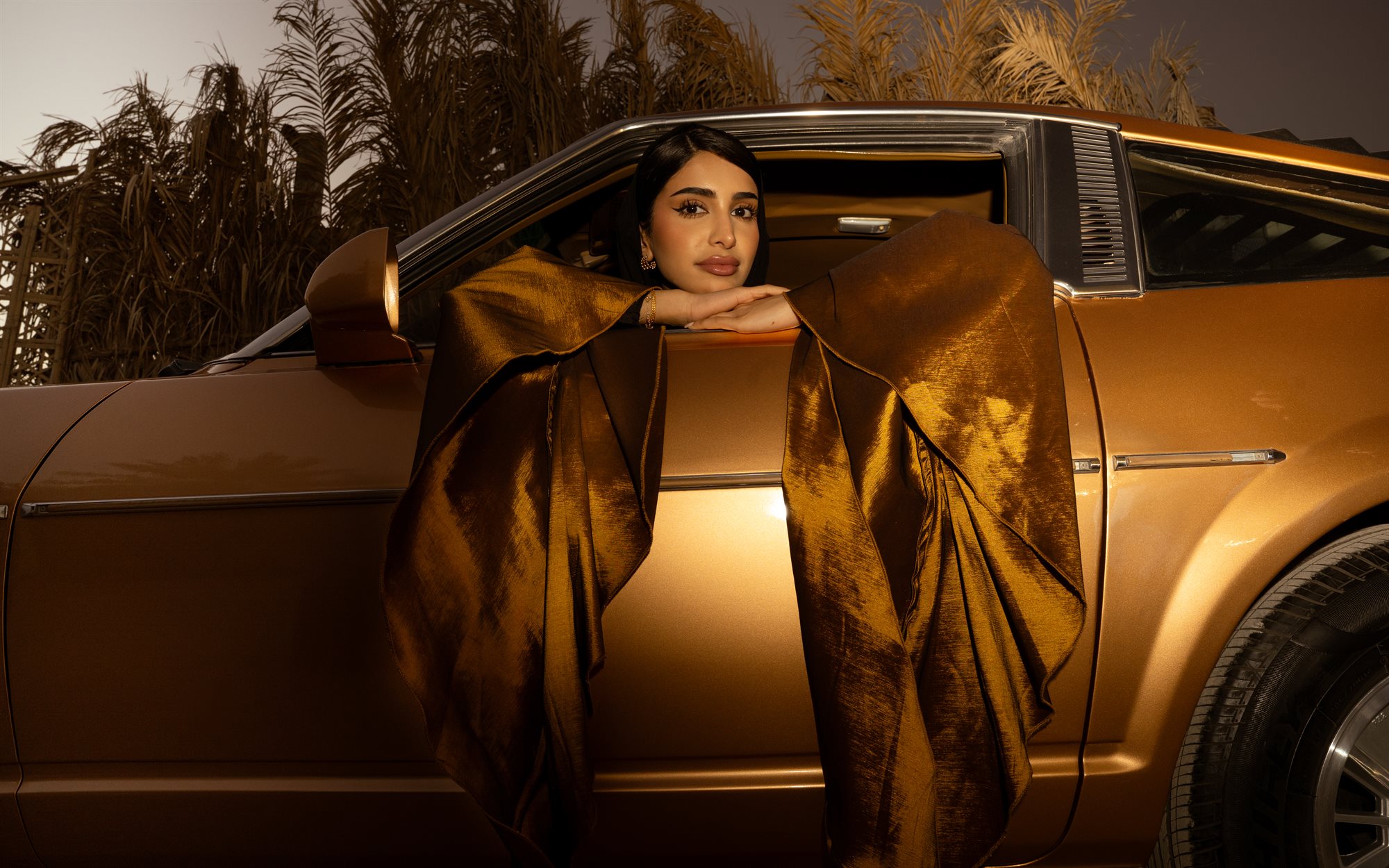 Majd & Thahab, gold cape draped over the car door