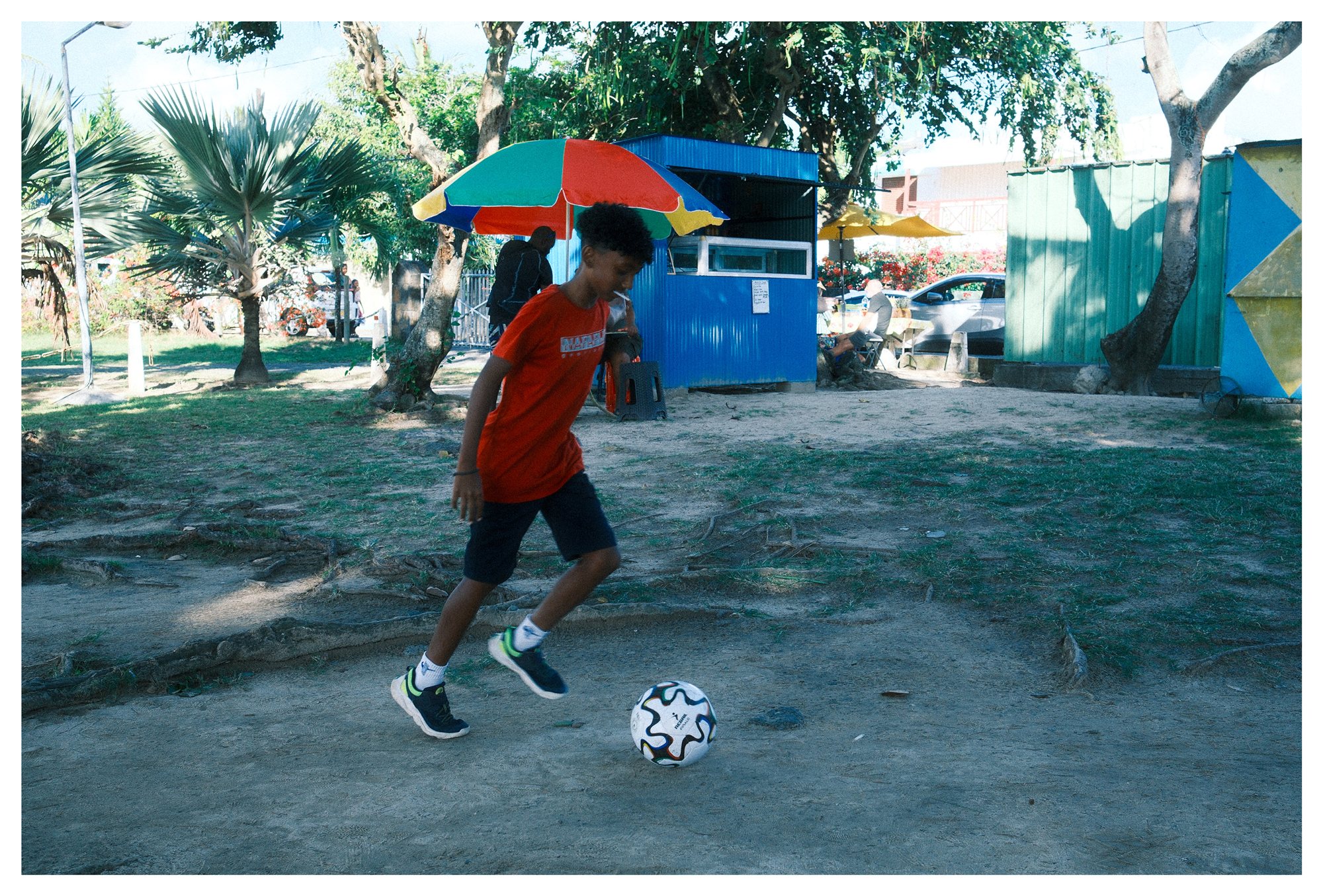 Mauritius, a boy playing football beneath a colorful beach umbrella