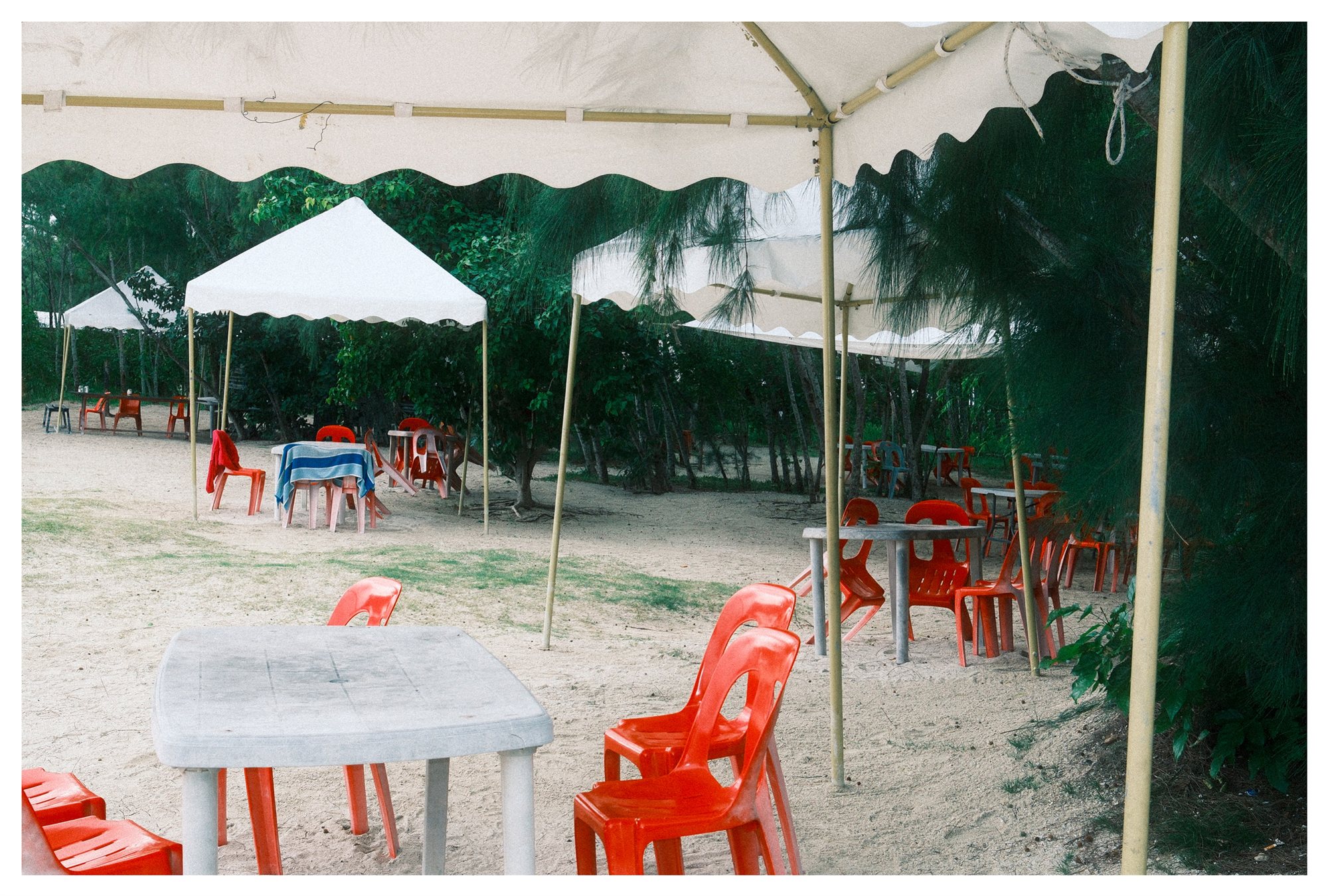 Mauritius, red plastic chairs beneath white beachside canopies